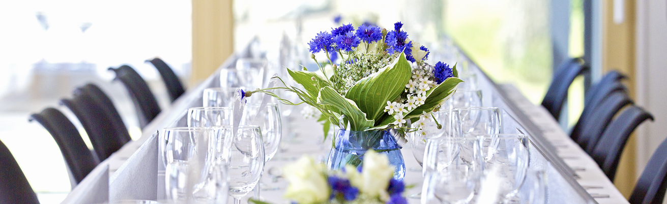Banner med dukat bord och blå blommor i en blå vas.